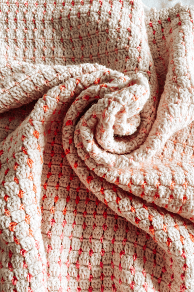A picture of a crochet blanket scrunched in the middle.