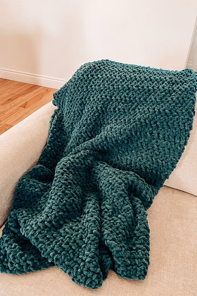 A picture of a blue crochet blanket on a couch