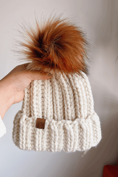 Chunky crochet beanie in cream topped with a faux fur pompom
